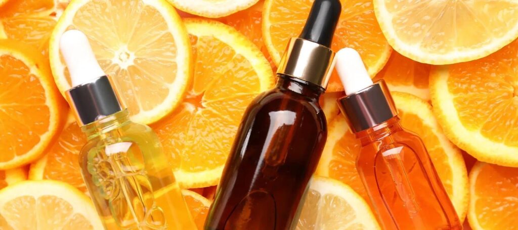 Three serum bottles with droppers sit on sliced oranges and lemons, showcasing a vibrant and citrusy skincare theme.